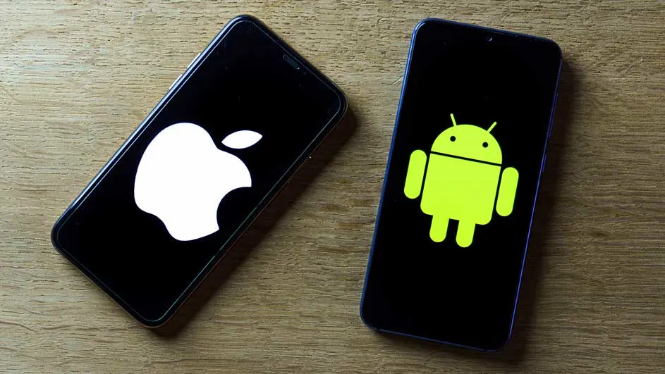 Deux smartphones sur une table en bois. L'un affiche un logo Apple blanc, l'autre un logo Android vert.