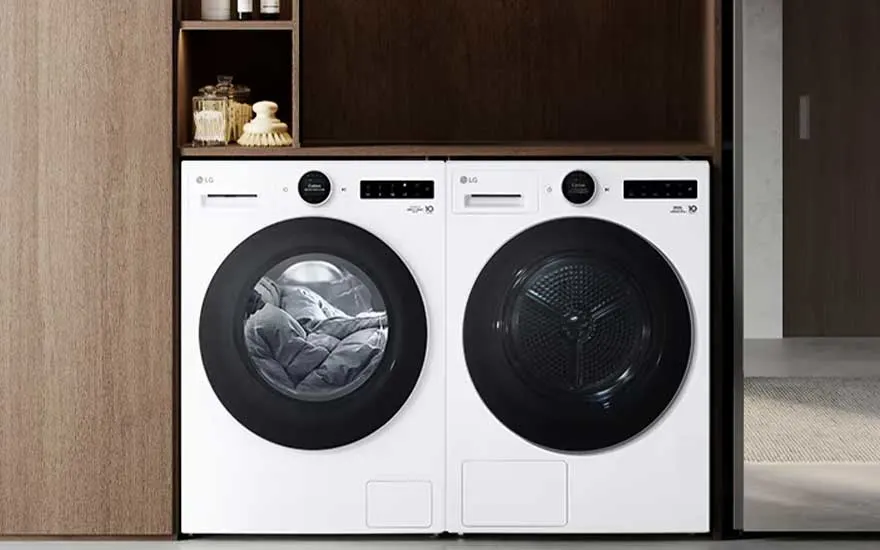 Witte LG-wasmachine en droger staan naast elkaar in een houten kast, met schappen voor flessen en kleine accessoires.