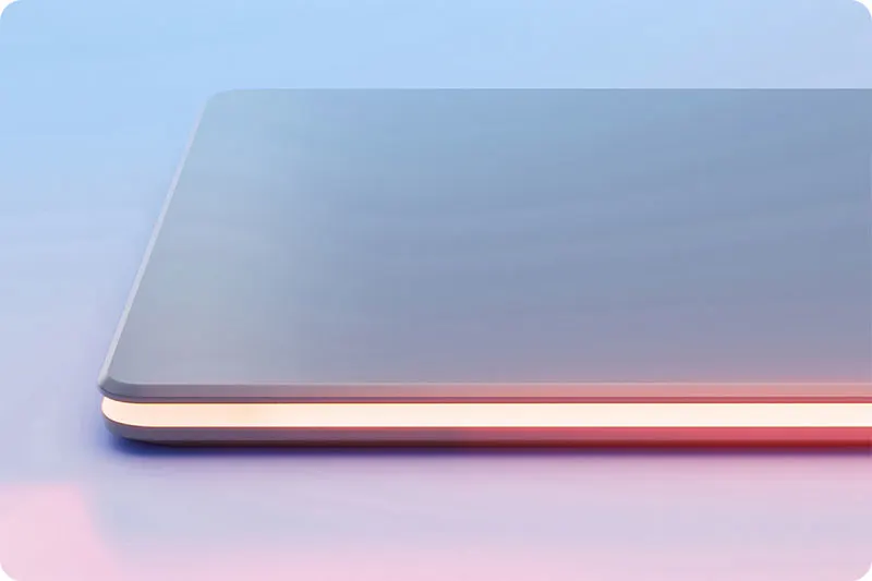 Une tablette grise est posée sur une surface bleue et rose, avec une bande lumineuse orange sur le bord.