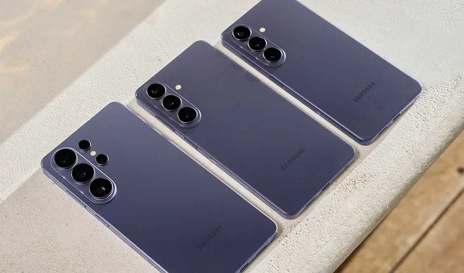 Drie paarse Samsung-smartphones liggen naast elkaar op een lichte rand, hun cameramodules glanzen subtiel in het zachte zonlicht aan de zwembadkant.