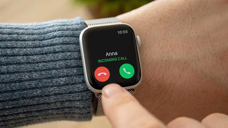Op een pols zit een zilveren smartwatch met een zwart scherm dat een inkomende oproep van "Anna" weergeeft, met rode en groene antwoordknoppen.