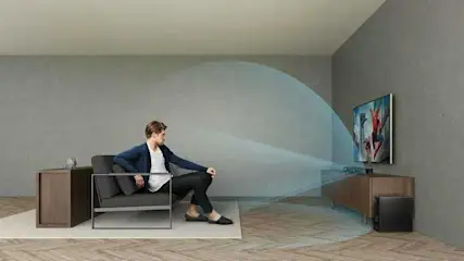 Salon avec téléviseur, meuble en bois, fauteuil gris et caisson de basse noir. Des ondes bleues indiquent la propagation du son.