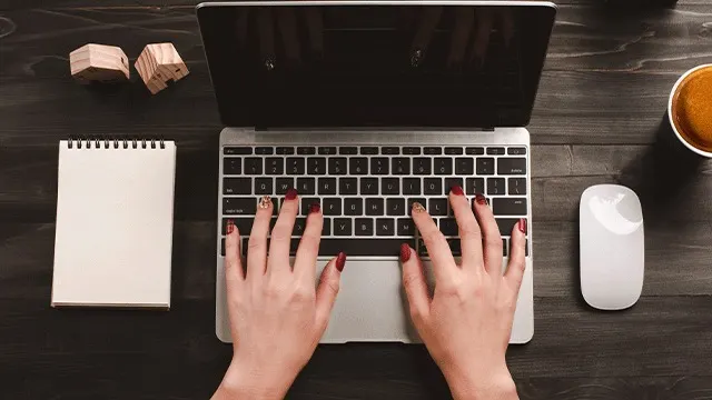 Vue de dessus d'un ordinateur portable, d'une souris, d'un carnet, de blocs en bois et d'une tasse sur une table en bois sombre.