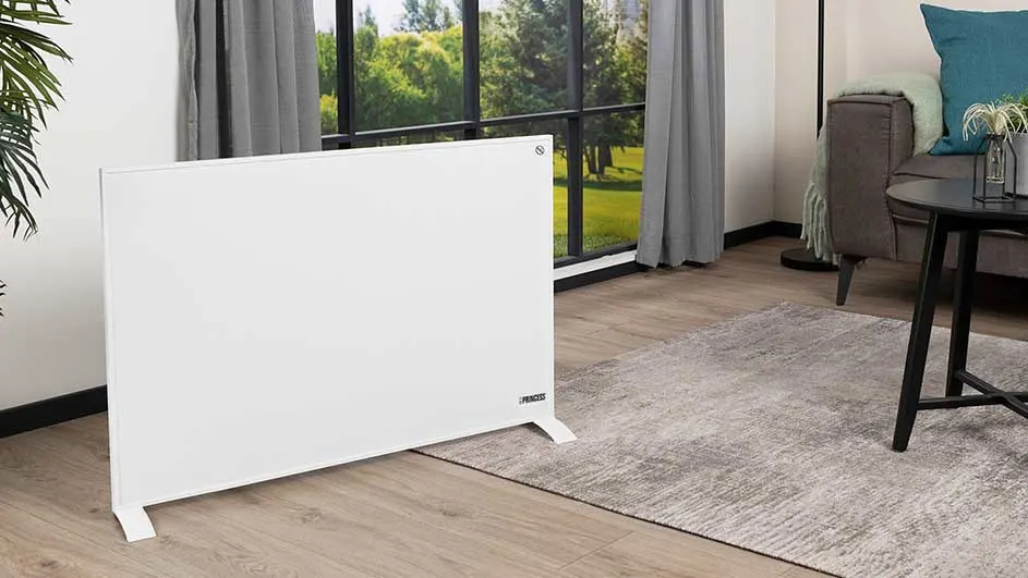 Radiateur blanc sur parquet clair, près d'une fenêtre avec rideaux gris. Tapis à motifs gris, canapé, table noire.