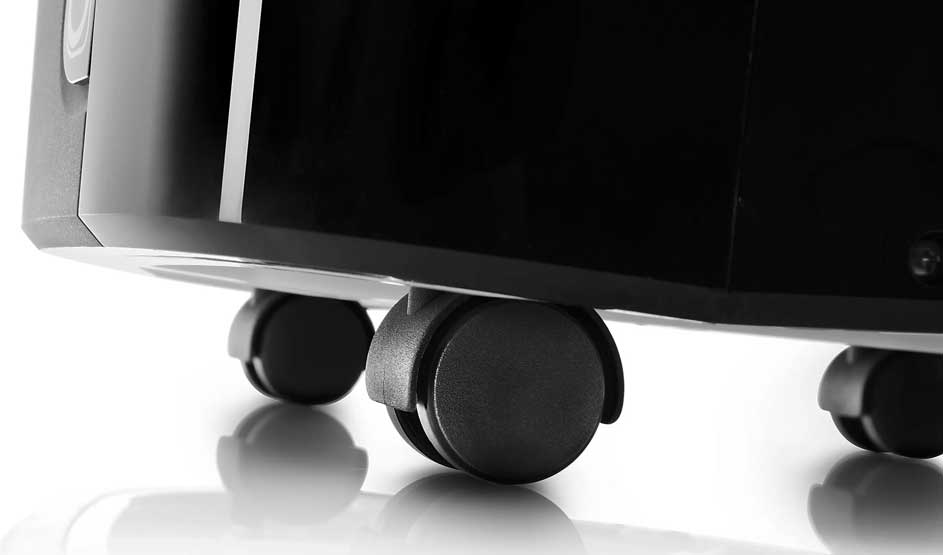 Gros plan sur des roulettes noires sous un appareil noir brillant, probablement un climatiseur mobile ; aucune marque n’est visible.