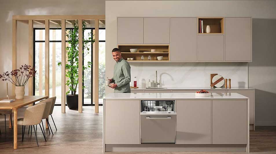 In a spacious, bright kitchen, a dishwasher on the island is open and full of dishes, in a modern space with warm dining area.