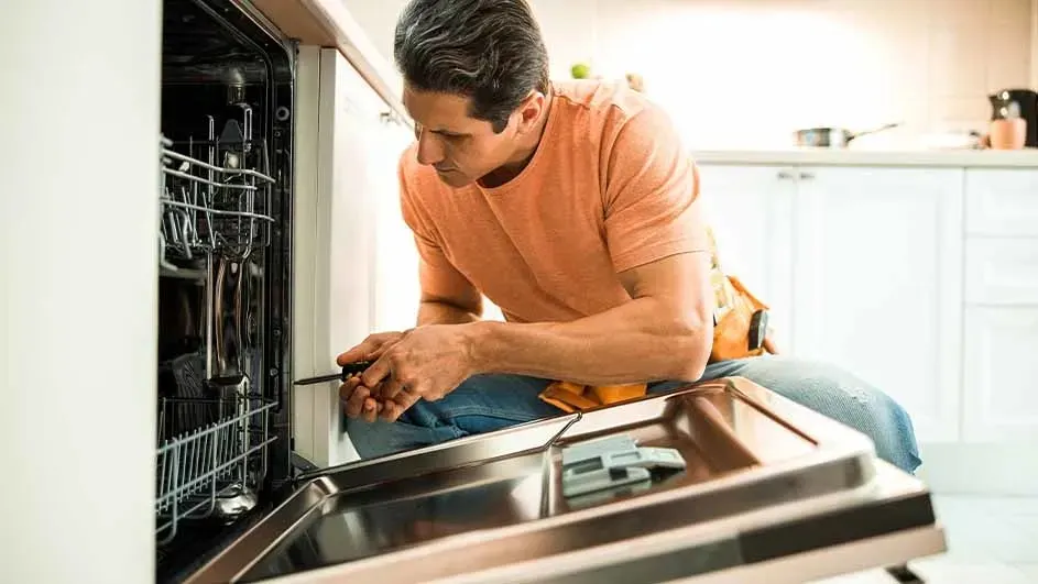Een vaatwasser met open deur in een witte keuken. Gereedschap is zichtbaar.