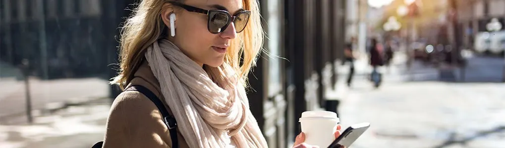 A street scene with buildings in the background. A coffee cup and a mobile phone are visible.