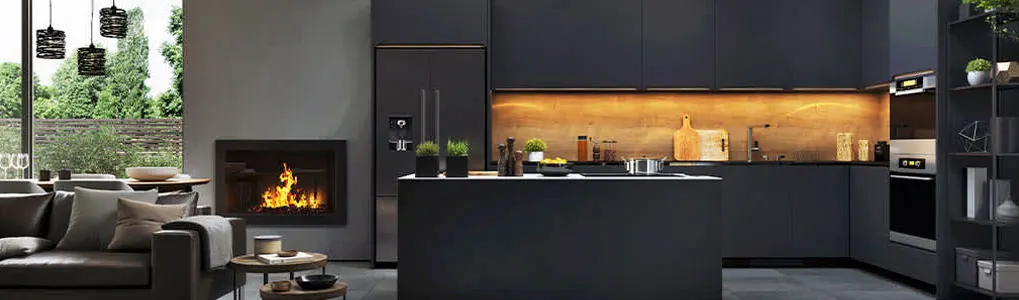 Vue d'un intérieur moderne avec cuisine noire, îlot central, cheminée allumée et salon avec canapé gris.