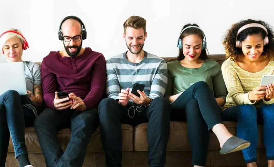 Cinq personnes assises sur un canapé marron, utilisant des appareils électroniques et portant des écouteurs sur fond blanc.