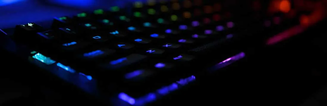Gros plan d'un clavier rétroéclairé multicolore sur un fond sombre, affichant des touches lumineuses bleues, vertes et rouges.