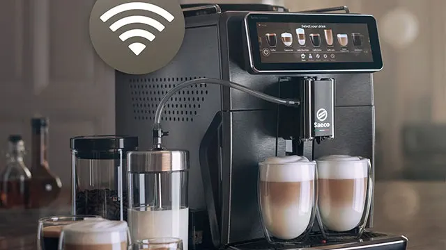 Zwarte Saeco-espressomachine met scherm, Wi-Fi-symbool, twee glazen latte macchiato, melk- en koffiereservoirs.