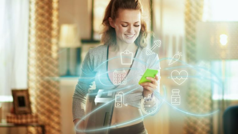 Een groen scherm van een smartphone met transparante pictogrammen, waaronder gewichten, een kalender en een hartslag, tegen een vage achtergrond.