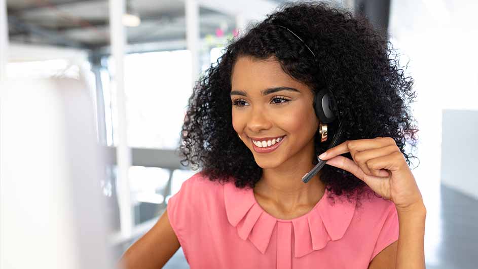 Een roze blouse en een headset in een lichte kantooromgeving.