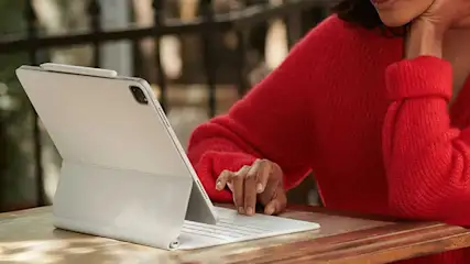 Tablette grise avec clavier et stylet sur une table en bois, avec un fond flou.