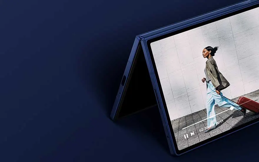 Un smartphone plié en forme de tente diffuse une vidéo montrant une femme marchant avec une valise, sur fond sombre.
