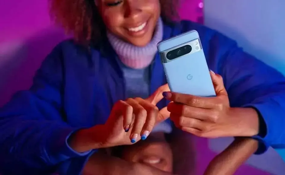 Une personne tient un téléphone bleu clair avec un appareil photo noir à l'arrière, sur fond violet et bleu.