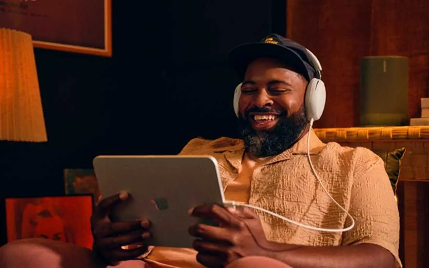 Un homme tient une tablette. Il porte un casque blanc et une casquette noire. Lampe et haut-parleur en arrière-plan.