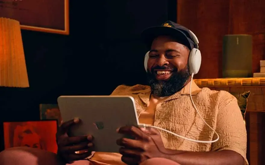 Un homme tient une tablette. Il porte un casque blanc et une casquette noire. Lampe et haut-parleur en arrière-plan.