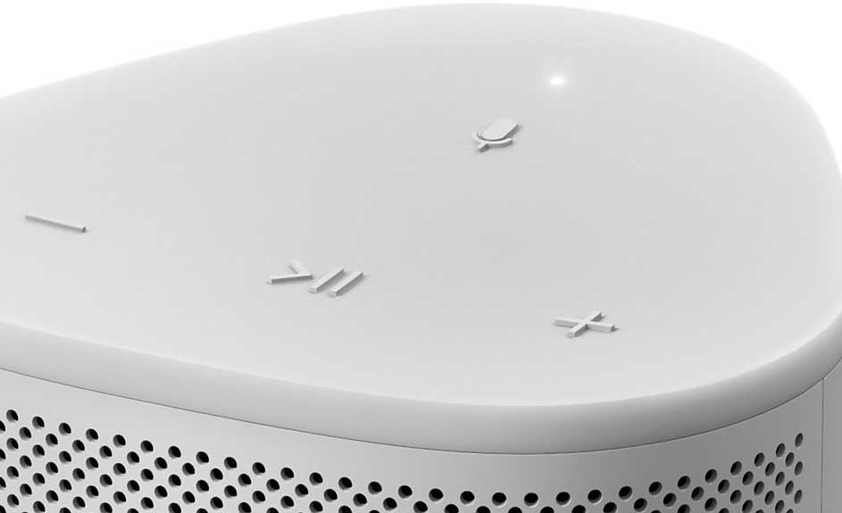 Vue rapprochée d'un haut-parleur blanc avec des boutons tactiles et une grille perforée.