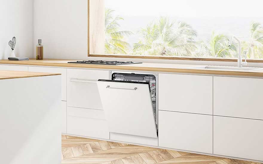 Un lave-vaisselle encastré, porte entrouverte, équipe une cuisine blanche avec touches bois et une vue panoramique sur des palmiers.