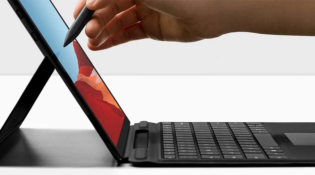 Un ordinateur portable noir avec un écran bleu et rouge est utilisé avec un stylet noir sur un fond blanc.