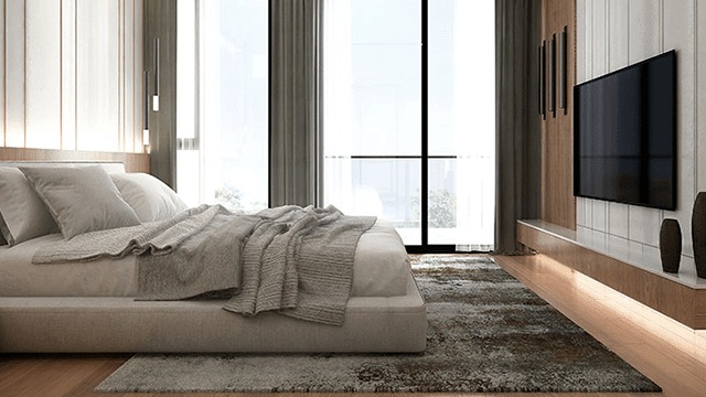 A bedroom features a bed with grey bedding, a large window with curtains, and a wall-mounted television.