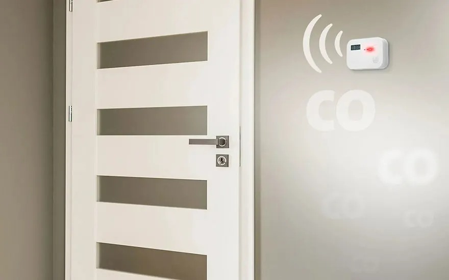 Witte deur met horizontale ramen naast een wand met CO-melder en vage CO-markering.