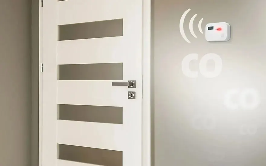 Witte deur met horizontale ramen naast een wand met CO-melder en vage CO-markering.