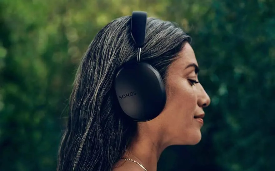 Gros plan d'un casque noir Sonos sur fond vert flou. Le casque est sur une surface, vu de profil.