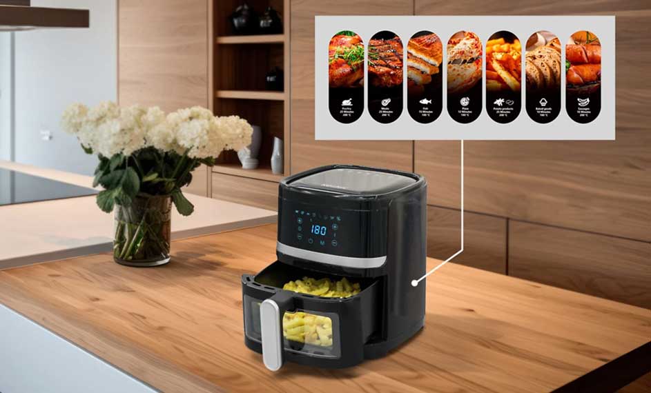 Een zwarte airfryer met frieten staat op een houten aanrecht, met een bloemenvaas en menugids op de achtergrond.