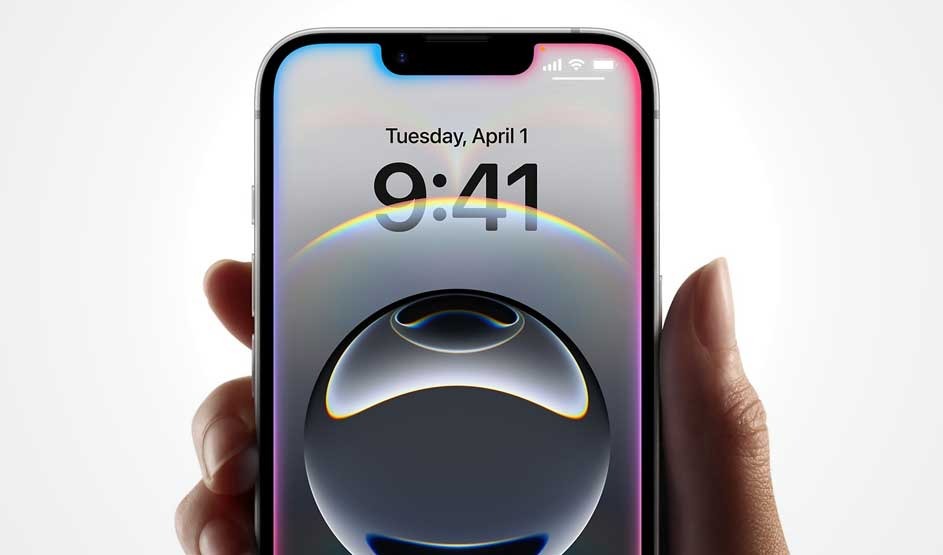 A hand holds an Apple iPhone, showing 9:41 on Tuesday, April 1. Sleek bezels, notch at the top, glossy orb wallpaper, bright, crisp display.