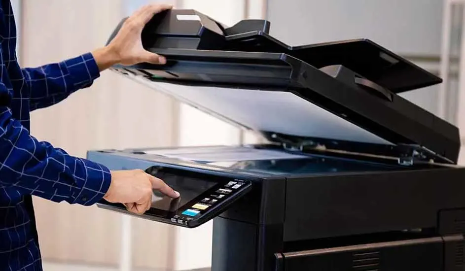 Een zwarte printer met een open scannerklep, bediend door een hand op het touchscreen.