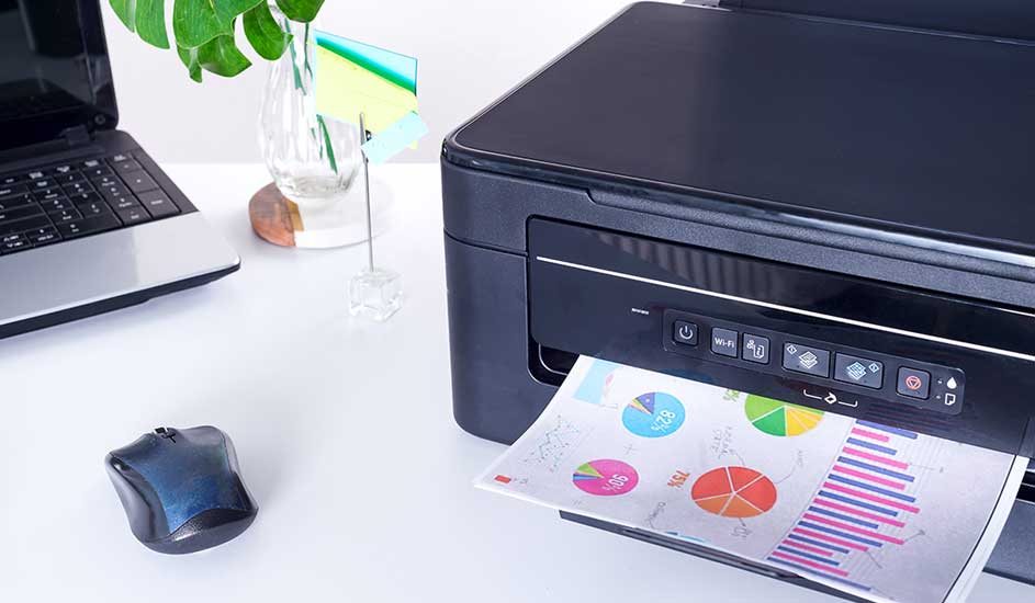 Zicht op een bureau met een printer die een pagina met grafieken print, een laptop, een muis en een vaas met planten.