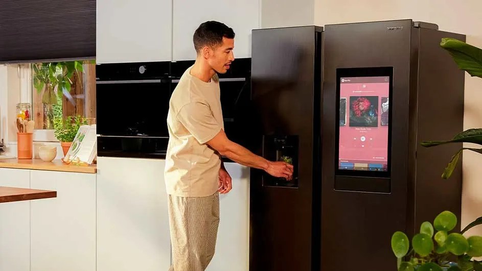 Cuisine moderne avec réfrigérateur noir, écran tactile, distributeur d'eau. Plantes vertes, comptoir en bois.