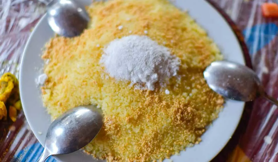 Couscous jaune avec une cuillère de sucre, entouré de trois cuillères sur une assiette blanche.