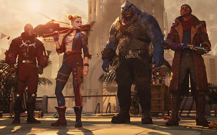 Vier gekostumeerde figuren staan voor een gebouw. Achter hen een helikopter, palmbomen en een zonsondergang.