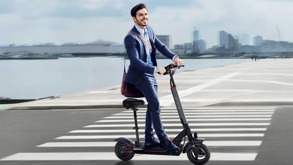 Een zwarte scooter met zitje staat op een zebrapad. Op de achtergrond is een rivier en een stad te zien.