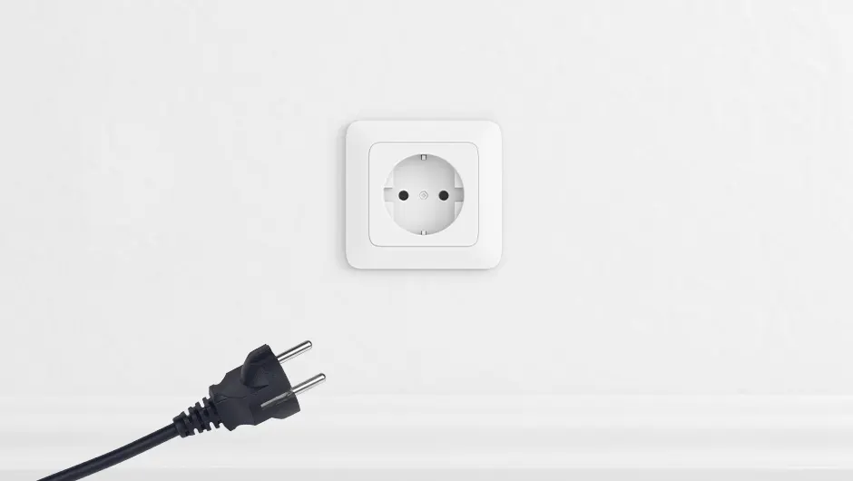 A white wall features a square electrical outlet with a visible plug nearby.