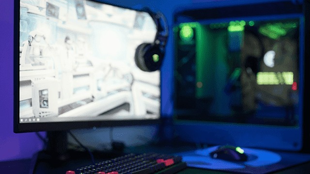 Un écran d'ordinateur affiche une image claire, avec un casque suspendu à côté. Un clavier et une souris reposent sur le bureau.