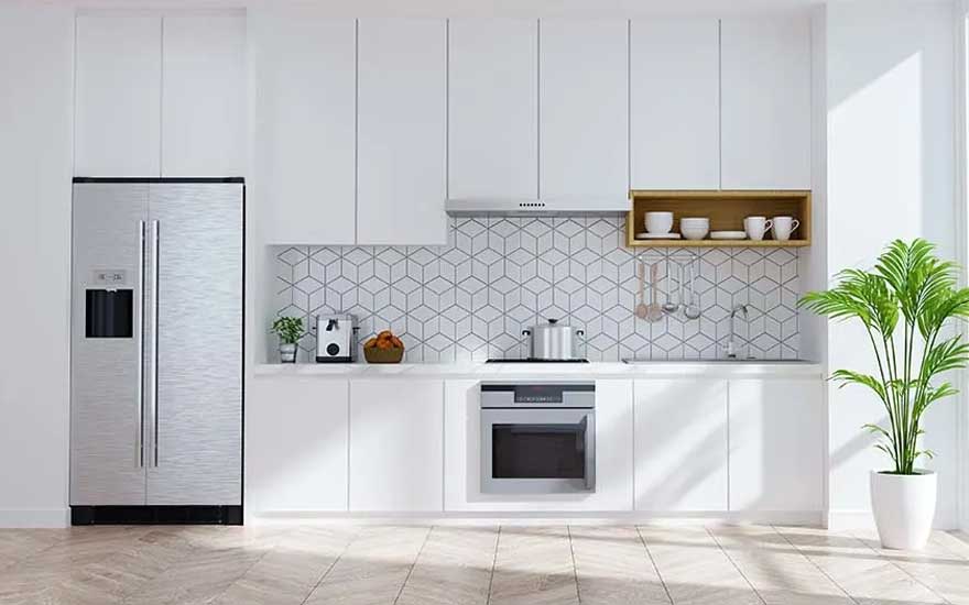 Cuisine lumineuse avec armoires blanches, réfrigérateur en acier inoxydable, dosseret à motifs géométriques et plante en pot.