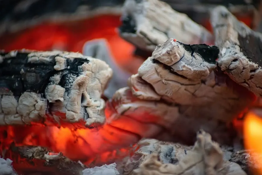 Close-up van sintels: zwart en grijs hout, roodgloeiend in de hitte.