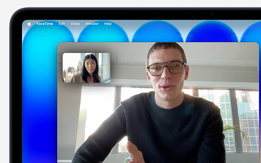 On the MacBook display a FaceTime call is in progress, showing a man in a large window and a woman in a smaller frame with city views.