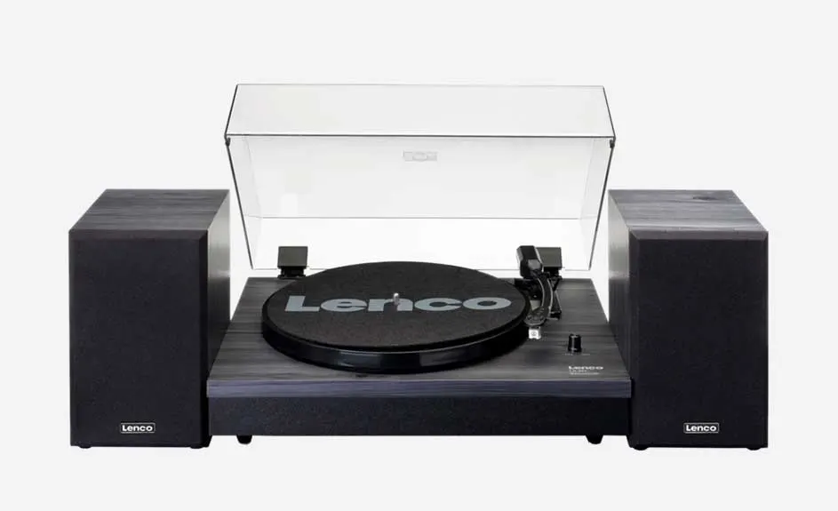 Platine vinyle Lenco noire avec couvercle transparent ouvert et deux enceintes noires sur fond blanc.
