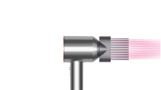 Een zilveren Dyson Supersonic föhn blaast roze lichtstralen tegen een witte achtergrond.