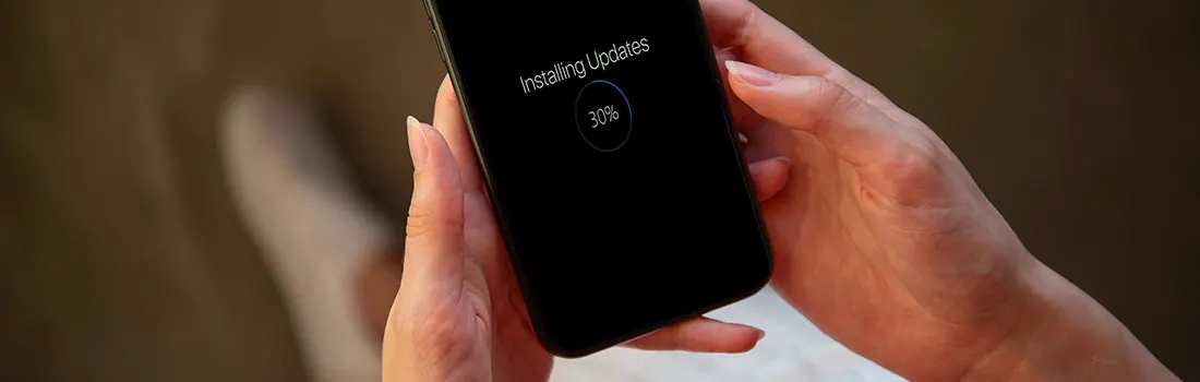 Een zwarte smartphone toont "Updates installeren" op het scherm, dat 30% voltooid is, terwijl het wordt vastgehouden.