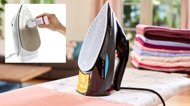 Un fer noir repose sur une planche à repasser blanche, avec une pile de linge coloré en arrière-plan. Insert d'un fer nettoyé.