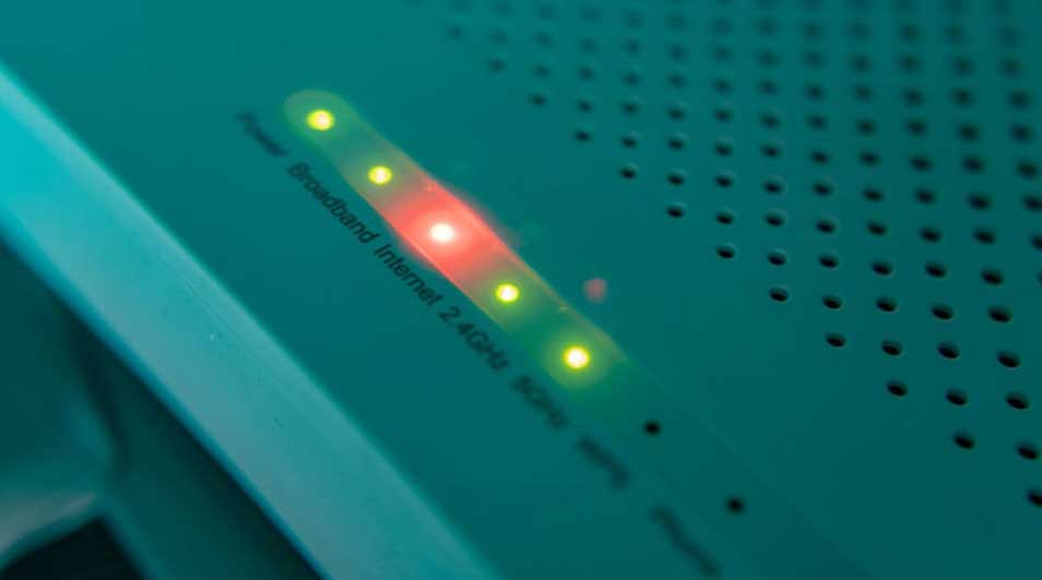 Detailopname van een modem met groene en rode LED-lampjes op een groene behuizing met gaatjes.