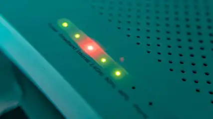Detailopname van een modem met groene en rode LED-lampjes op een groene behuizing met gaatjes.