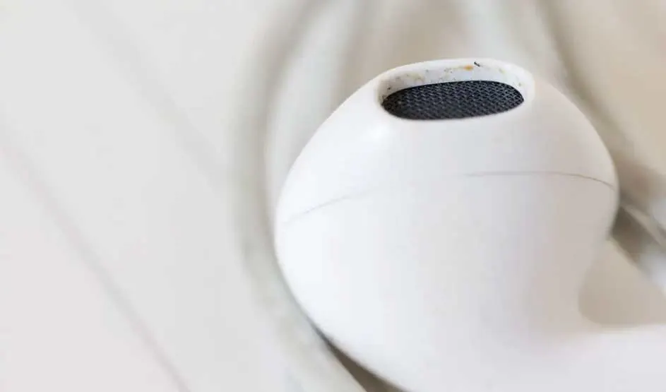 Un écouteur blanc avec l'intérieur un peu sale posé sur un tissu blanc froissé. L'image est claire et mise au point.